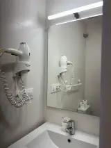 Lavabo con espejo iluminado y secador de pared del baño privado de la Habitación Individual